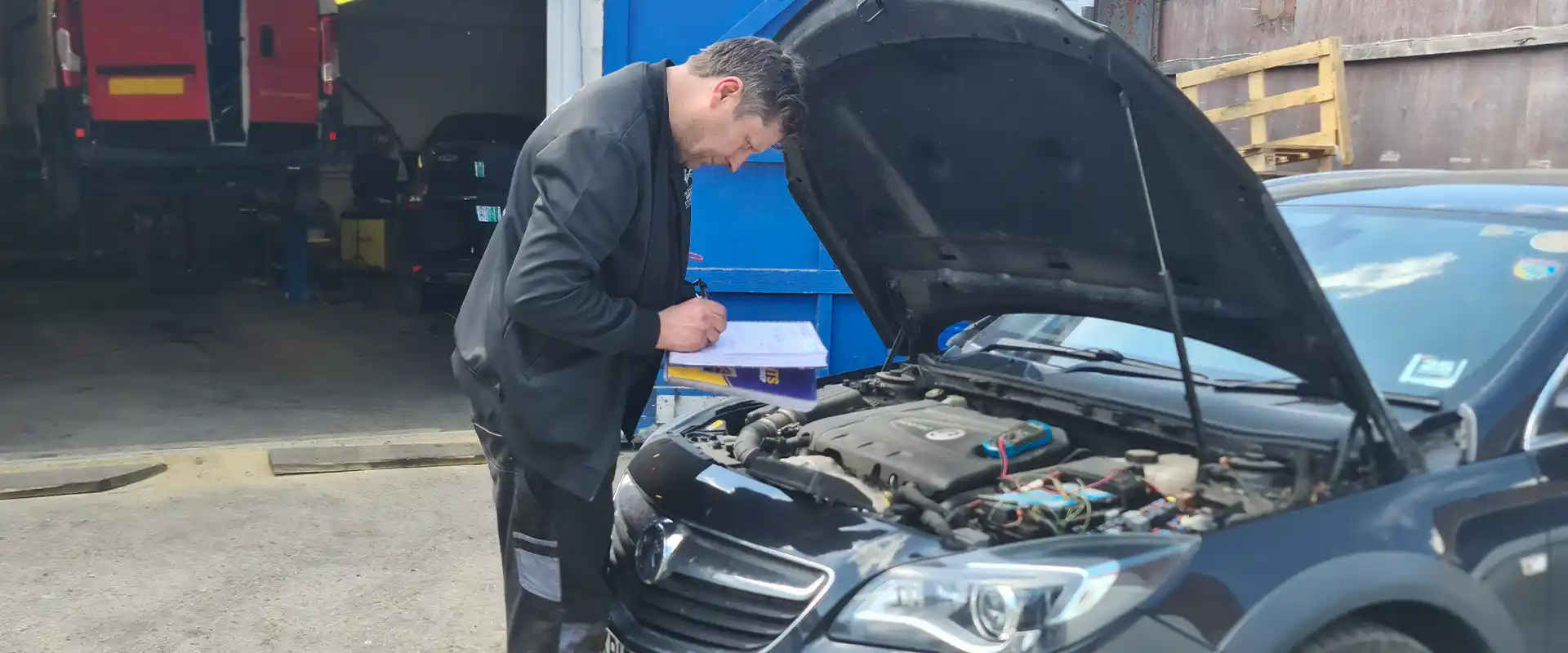 Mechanic reviewing engine checklist in front of garage